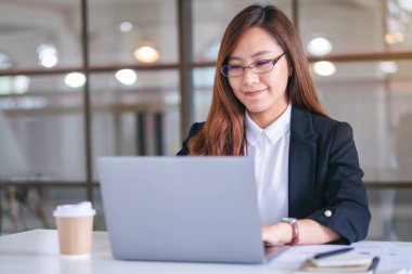 İş kadınının ofiste çalışırken dizüstü bilgisayar kullanıp daktilo kullandığı yakın plan resmi