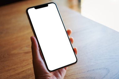 Boş beyaz masaüstü ekran ile siyah bir cep telefonu tutan bir elin görüntüsü 
