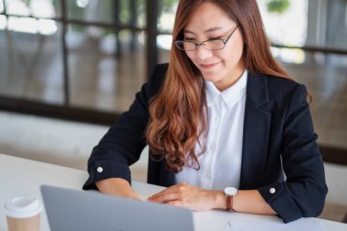 İş kadınının ofiste çalışırken dizüstü bilgisayar kullanıp daktilo kullandığı yakın plan resmi