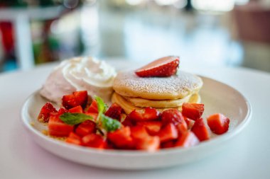 Masada bir tabak çilekli krep ve krem şanti.