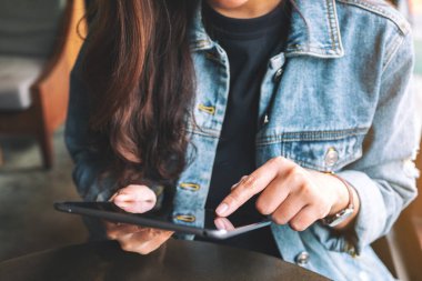 Kafede otururken elinde tablet bilgisayar kullanan bir kadının yakın plan görüntüsü