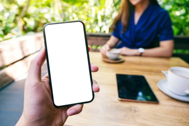 Kafe 'de kahve içen, elinde siyah cep telefonu olan beyaz ekranlı bir adamın görüntüsü.