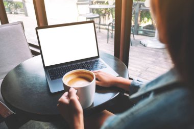 Masasında kahve fincanı olan ve boş beyaz masaüstü ekranı olan bir kadının laptopa dokunuşunu ve dokunuşunu görüntüle. 