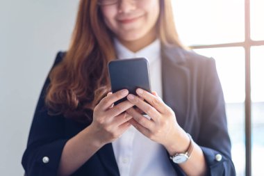 Cep telefonu tutan ve kullanan bir iş kadınının yakın plan görüntüsü