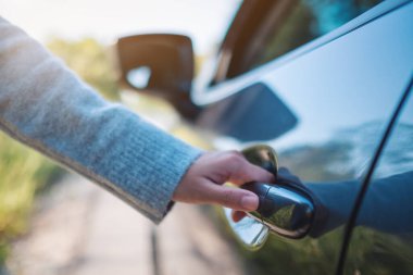 Arabanın kapısını açan bir kadının yakın plan görüntüsü.