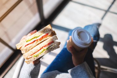 Sabahları elinde kepekli sandviç ve kahve tutan ve yiyen bir kadının en iyi görüntüsü.