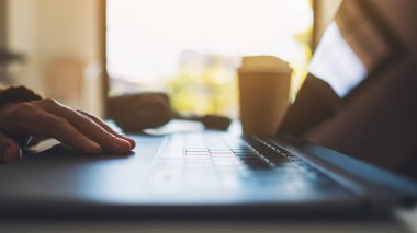 Masadaki dizüstü bilgisayarda çalışan ve yazan bir kadının ellerinin yakın plan görüntüsü.