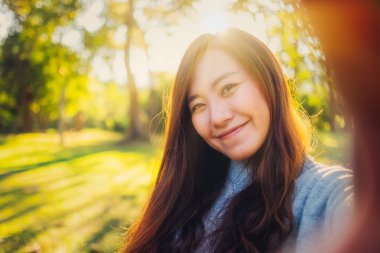 Parkta selfie çeken mutlu Asyalı bir kadının portresi.