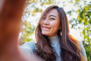 Parkta selfie çeken mutlu Asyalı bir kadının portresi.