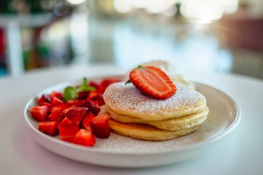 Masada bir tabak çilekli krep ve krem şanti.