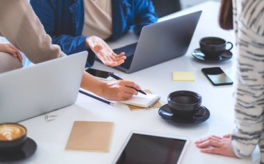 Ofiste dizüstü bilgisayarla tartışan ve yazan bir grup işadamı.