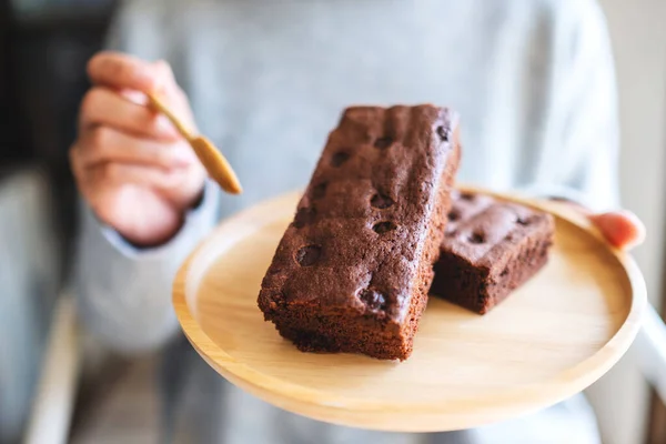 Closeup image of a woman eating delicious brownie cake with spoon