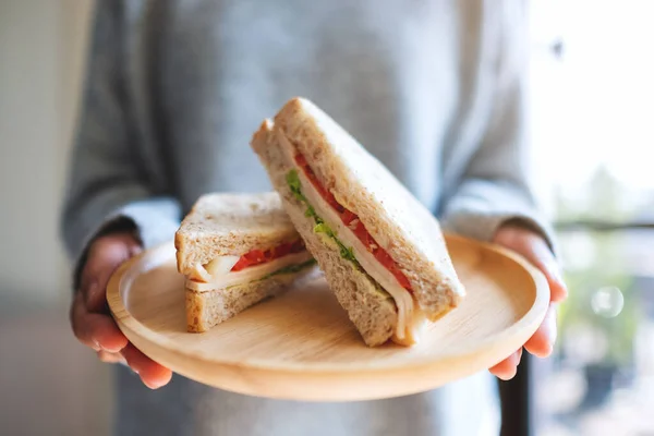 Una Mujer Sosteniendo Dos Piezas Sándwich Trigo Entero Plato Madera —  Fotos de Stock