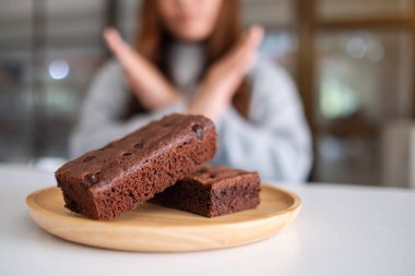 Tahta tabakta browni kekini reddeden bir kadın kollarını çapraz işareti yapıyor.