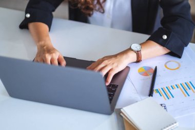 İş kadını dizüstü bilgisayarında ofis masasında kağıt işleriyle daktilo kullanıyor.