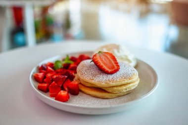 Masada bir tabak çilekli krep ve krem şanti.