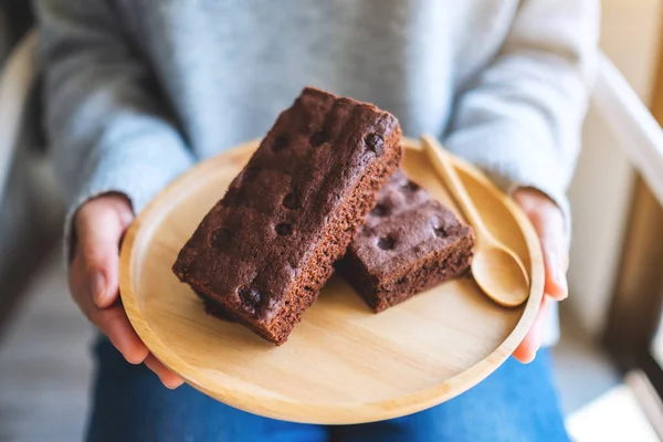 Yakından bakınca, elinde kek olan bir kadının ahşap tabakta görüntüsü.