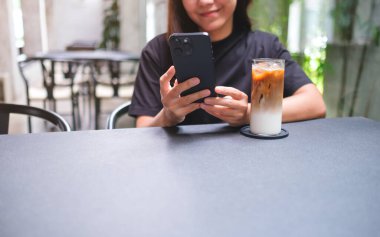 Kafede cep telefonu tutan ve kullanan bir kadının yakın plan görüntüsü