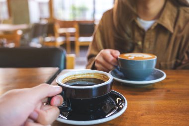 Kafede elinde kahve tutan ve içen bir çiftin yakın çekimi.