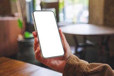 Kafede boş masaüstü ekranı olan cep telefonu tutan bir kadının görüntüsü