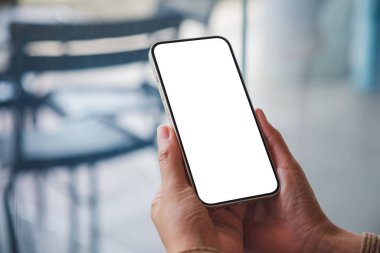 Kafede boş masaüstü ekranı olan cep telefonu tutan bir kadının görüntüsü