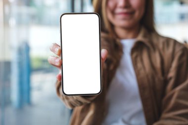 Elinde cep telefonu tutan ve gösteren beyaz ekranlı genç bir kadının görüntüsü.