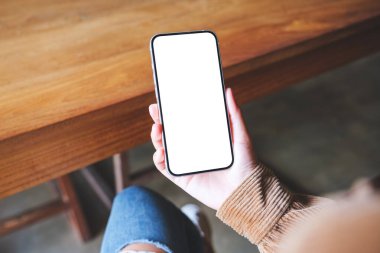 Boş masaüstü ekran ile cep telefonu tutan bir kadının üst görünüm görüntüsü