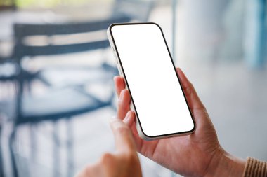 Kafede boş masaüstü ekranı olan cep telefonu tutan bir kadının görüntüsü