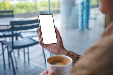 Kafede kahve içerken boş masaüstü ekran ile cep telefonu tutan ellerin görüntüsü