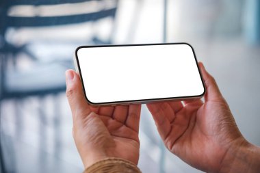 Kafede boş masaüstü ekranı olan cep telefonu tutan bir kadının görüntüsü