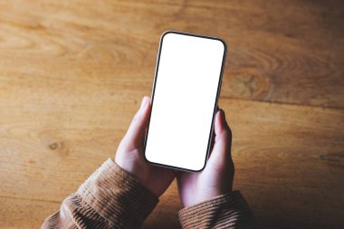Boş masaüstü ekran ile cep telefonu tutan bir kadının üst görünüm görüntüsü