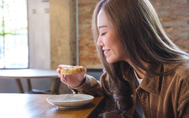 Çikolata parçalı kurabiyeye sarılıp yiyen genç bir kadın.