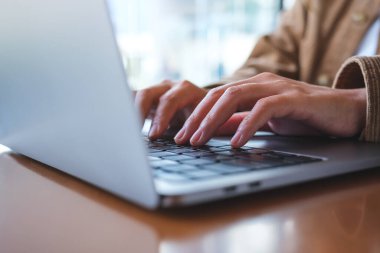 Laptop bilgisayar klavyesinde çalışan ve yazan bir kadının yakın plan resmi