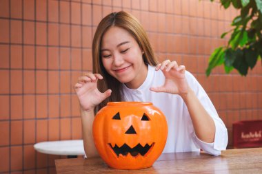 Cadılar Bayramı festivali konsepti için balkabağı kasesiyle oynayan güzel bir genç kadının portresi.