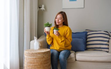 Evdeki çiçeklerle ilgilenen güzel bir genç kadının portresi.