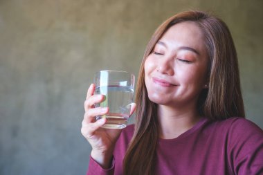 Bir bardak su tutan, gözleri kapalı genç bir kadının portresi.