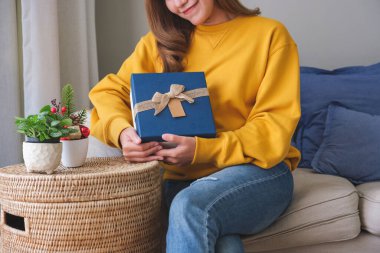 Evinde bir hediye kutusu tutan ve alan genç bir kadının yakın plan resmi.