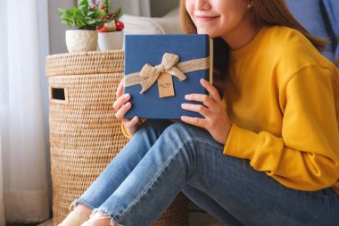 Evinde bir hediye kutusu tutan ve alan genç bir kadının yakın plan resmi.