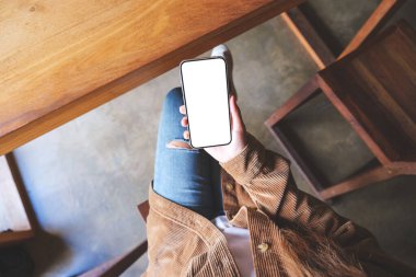 Boş masaüstü ekran ile cep telefonu tutan bir kadının üst görünüm görüntüsü