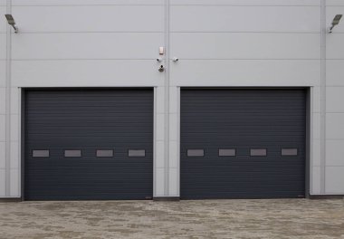 Fabrikada, depoda, garajda ve endüstriyel depoda kullanılan otomatik metal paten kapılarına yakın çekim. Fabrika, depo ya da hangar için kullanılan sürgülü kapı ya da paten panjuru.