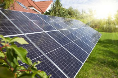 Güneş paneli, fotovoltaikler, alternatif elektrik kaynağı - ev tarafından bahçeye yerleştirildi. Modern bir villanın bahçesindeki güneş panelleri.