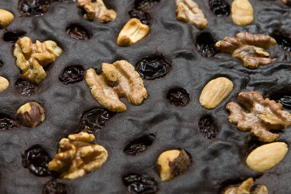 Brown, homemade walnut cake. Closeup background. Cake texture with raisins and walnuts close-up.