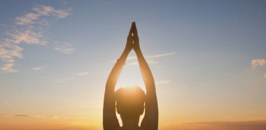 Yoga yapan bir kadın, gün batımı. İyileşme konsepti. Siluet genç kadın gün batımında yoga yapıyor. Huzur ve konsantrasyon..