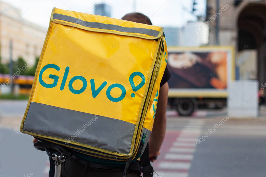 Warsaw, Poland - Jun 05, 2021: Glovo cyclist on the street in the city center. Food delivery. Close up of a bag.