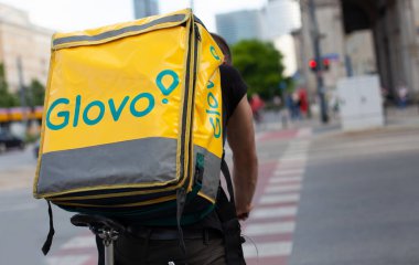 Polonya, Varşova - Haziran 05, 2021: Şehir merkezindeki sokakta Glovo bisikletçisi. Yemek servisi. Bir çantayı kapat..
