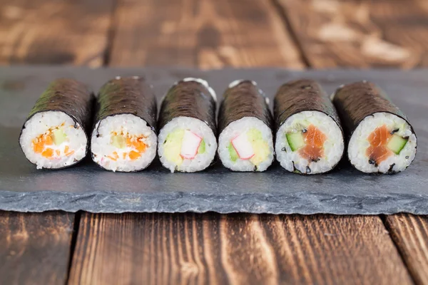 Hemgjord maki sushi rullar på en skiffer styrelse Stockbild