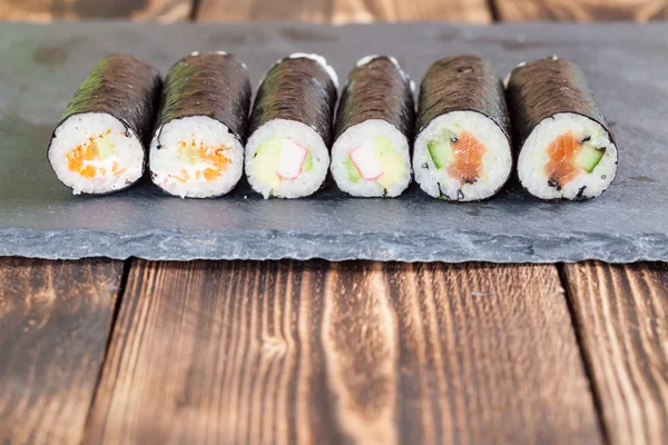 Rotoli di sushi maki fatti in casa su una tavola di ardesia — Foto Stock