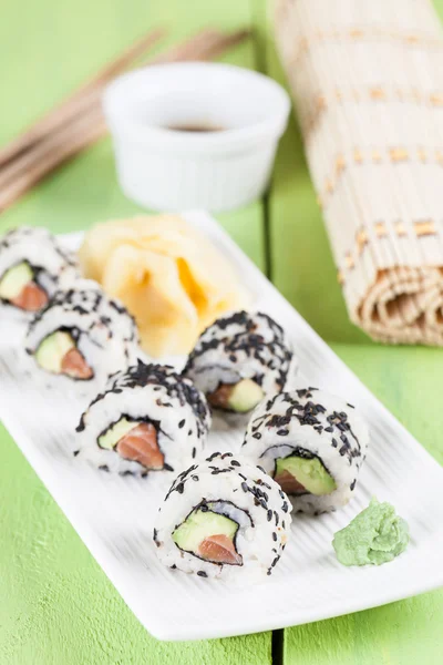 Uramaki-Sushi mit Avocado, rohem Lachs und schwarzem Sesam — Stockfoto