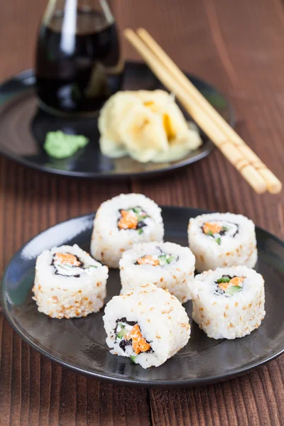 Uramaki sushi com cenoura, pepino, surimi e se branco torrado — Fotografia de Stock