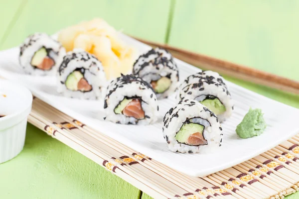 Uramaki-Sushi mit Avocado, rohem Lachs und schwarzem Sesam — Stockfoto
